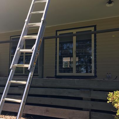 Painter on a ladder painting house trim.